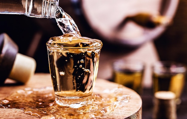 Glas goldener Rum mit Flasche Flasche, die Alkohol in ein kleines Glas gießt Brasilianisches Exportgetränk Brasilianisches Produkt für den Export destilliertes Getränk, bekannt als Brandy oder Pinga Tag des Cachaca