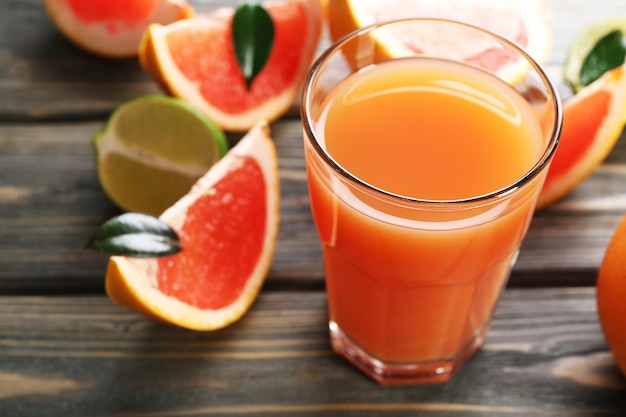 Glas Grapefruitsaft und frische Früchte auf Holzhintergrund