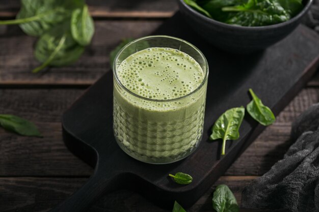 Glas hausgemachter gesunder grüner Smoothie mit frischem Babyspinat auf dunklem Hintergrund. Konzept für Essen und Trinken, Diät und gesunde Ernährung