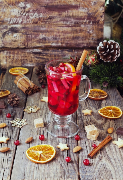 Glas heißer Glühwein für das neue Jahr mit Zutaten zum Kochen, Nüssen und Weihnachtsdekorationen