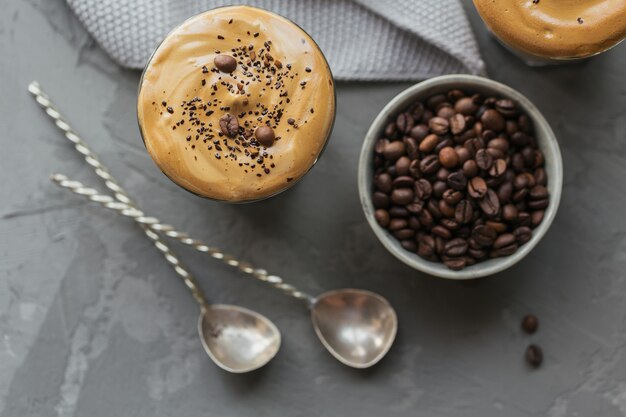 Glas Iced Dalgona Coffee, ein trendiger, flauschiger, cremiger, geschlagener Kaffee und Milch auf Grau.
