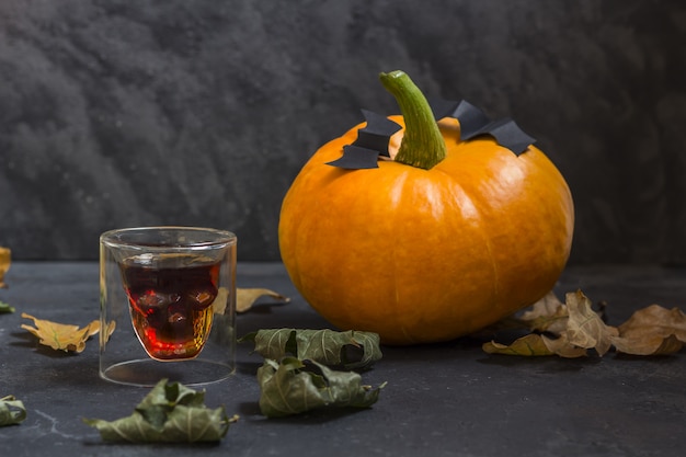 Â Glas in Form eines Schädels und Herbst Halloween Kürbisse auf einem dunklen Hintergrund.