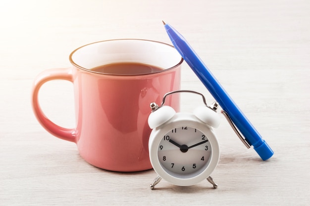 Glas Kaffee auf Tisch mit Stift und Uhr