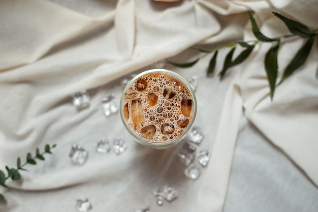 Glas Kaffee mit Milch auf einer weißen Leinwand