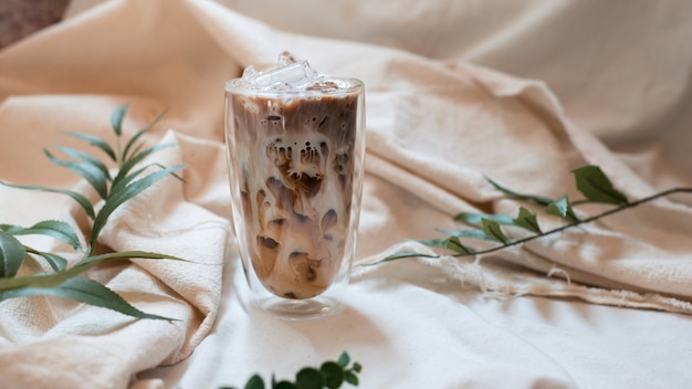 Glas Kaffee mit Milch auf weißer Leinwand