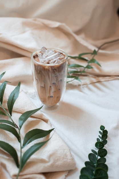 Glas Kaffee mit Milch auf weißer Leinwand