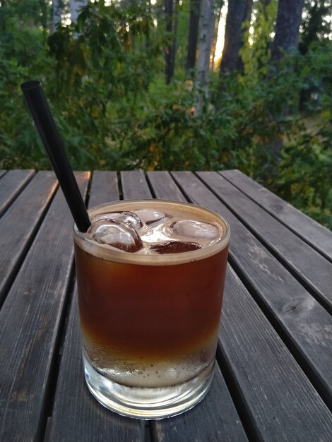 Glas Kaffeecocktail Tonic Espresso mit Eis auf dem Holztisch im Park