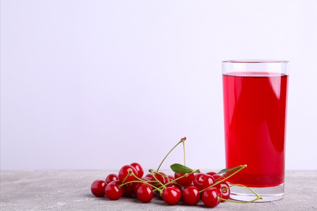 Glas Kirschsaft und Beeren auf Grau mit Kopienraum