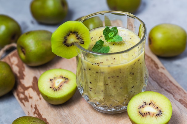 Glas Kiwisaft mit frischen Früchten auf Holztisch