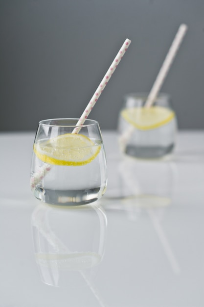Glas klares Wasser mit Zitrone und Stroh.