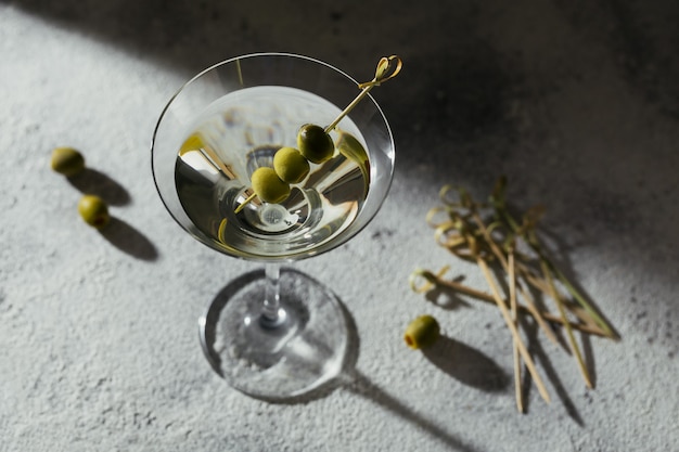 Glas klassischer trockener Martini-Cocktail mit Oliven auf grauem Stein