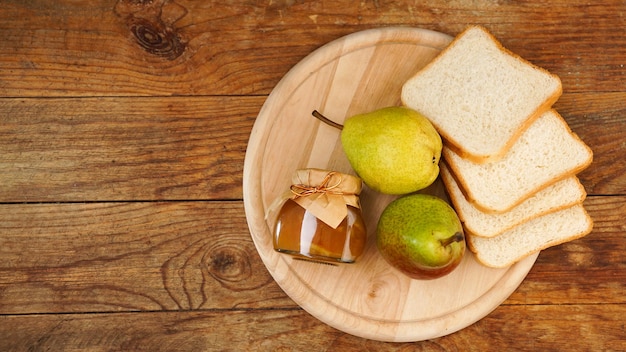 Glas leckere Birnenmarmelade mit Brot und frischen Birnenfrüchten auf Holztisch Draufsicht