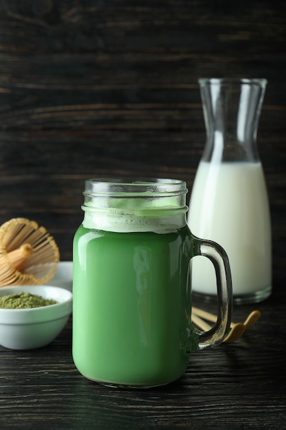 Glas Matcha Latte und Zubehör für die Herstellung auf Holzuntergrund