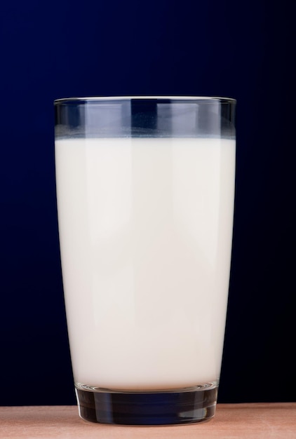 Foto glas milch auf holztisch auf dunkelblauem hintergrund