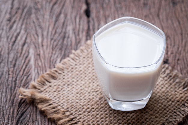 Glas Milch auf Holztisch.