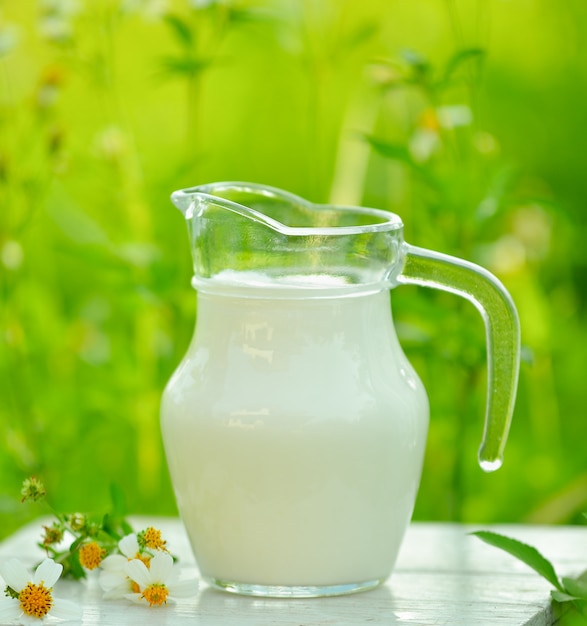 Glas Milch auf weißem Tisch im Morgengarten