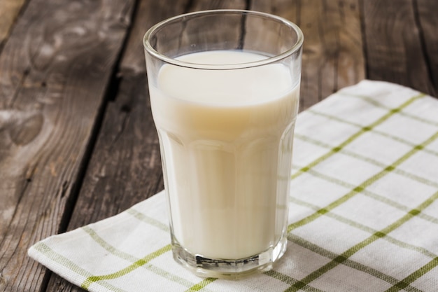 Glas Milch auf weißer Serviette über dem Holztisch