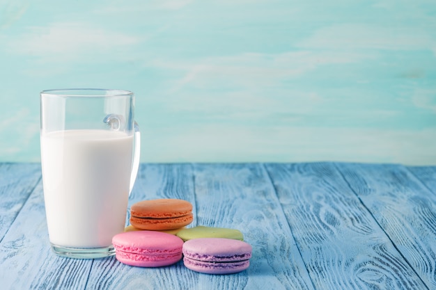 Glas Milch mit französischer Makrone auf blauem Tisch