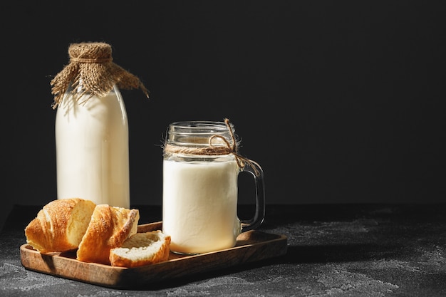 Glas Milch mit geschnittenem Baguette auf Holzbrett