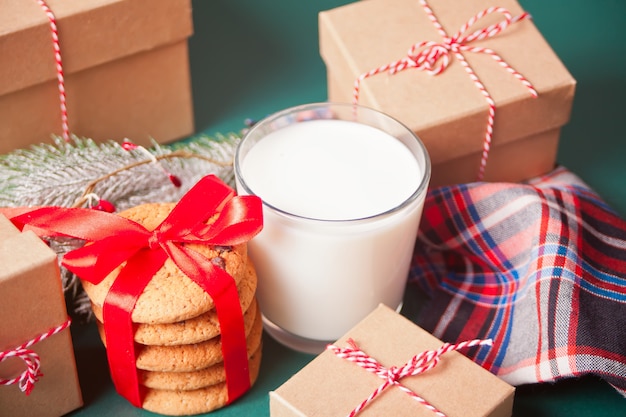 Glas Milch, Plätzchen, Weihnachtsgeschenkboxen und Kiefer verzweigen sich auf die grüne Tabelle