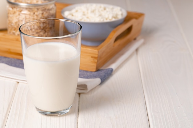 Glas Milch und Haferflocken auf Holztisch