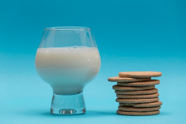 Glas Milch und Kekse auf blauem Hintergrund