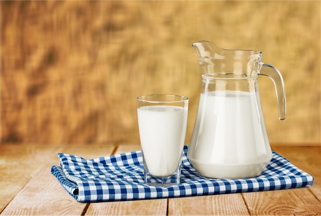 Glas Milch und Krug auf Holztisch