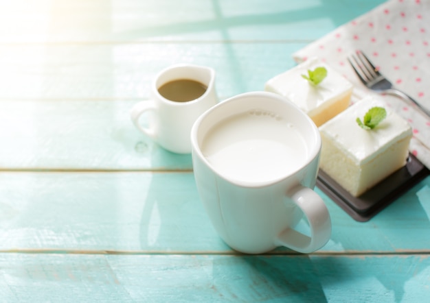 Glas Milch- und Milchkuchen köstlich auf der hölzernen Tabelle mit Schatten von einem Fensterrahmen
