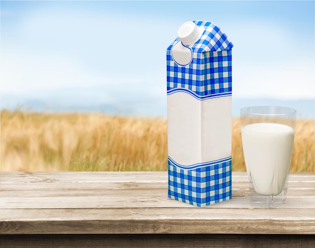 Glas Milch und Paket auf hölzernem Hintergrund