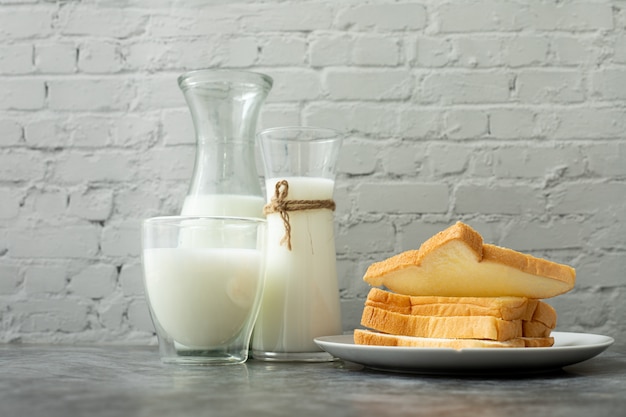 Glas Milch und Scheibenbrot auf Küchentisch.