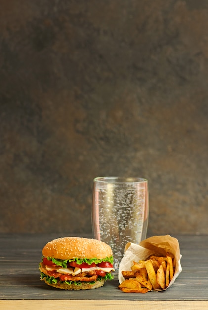 Glas Mineralwasser und Hamburger, salzige Snacks, Brezeln, Pommes.