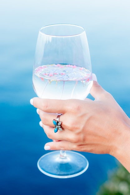 Glas mit Blumen und Hand.