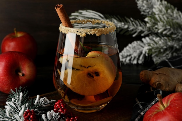 Foto glas mit cideräpfeln und weihnachtsbaumzweigen auf dunklem holzhintergrund in naher nähe