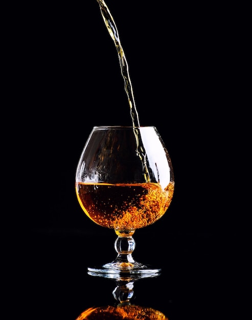 Glas mit Cognac auf schwarzem Hintergrund