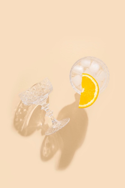 Glas mit einem Cocktail mit Orangenscheibe auf beigem Hintergrund Draufsicht flach gelegt