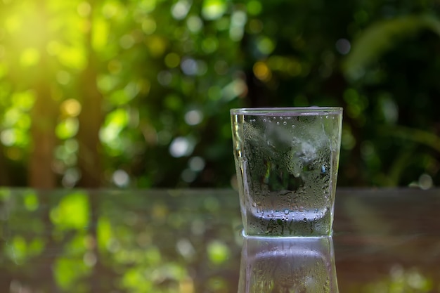 Glas mit Eis Setzen Sie auf Holzboden Grünen Hintergrund der Natur