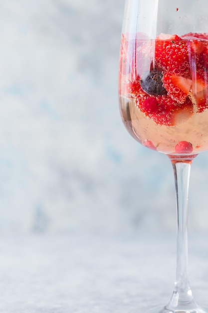 Glas mit Eis Sommer hausgemachter kalter roter Sangria-Cocktail mit Erdbeere im Glas auf blauer Wand. Konzept des Urlaubs, Sommer