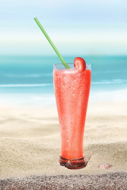 Glas mit Erdbeersaft auf dem Strandsand