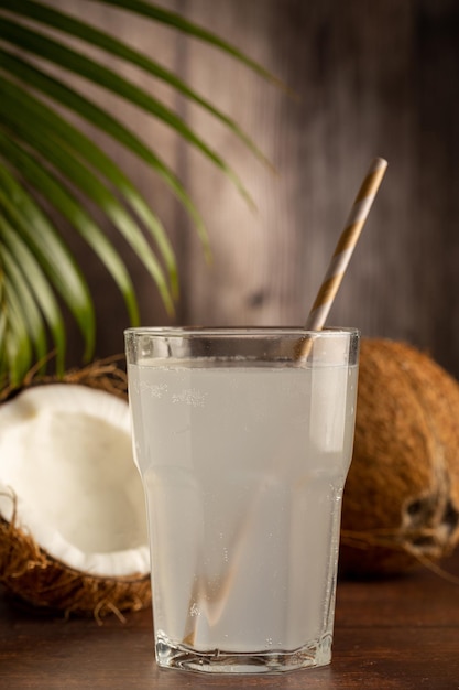 Glas mit frischem Kokoswasser und Kokosnüssen auf dem Tisch