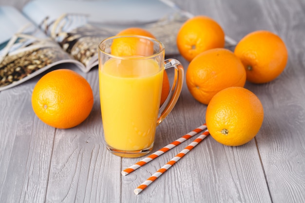 Glas mit frischem Orangensaft mit frischen Früchten auf dunklem Tisch