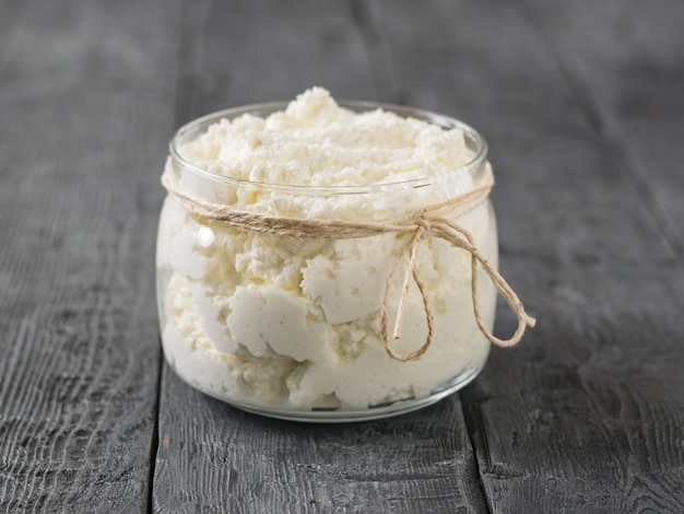 Glas mit frischem Quark auf einem Holztisch.