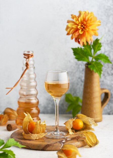 Glas mit hausgemachtem Wein oder Likör aus reifen Physalis-Früchten Alkoholgetränkkonzept Selektiver Fokus