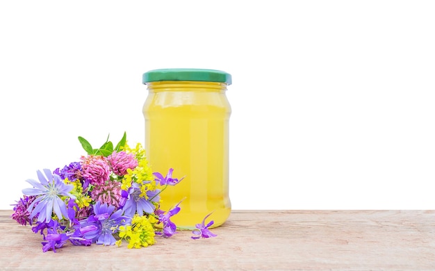 Glas mit Honig und einem Blumenstrauß auf weißem Hintergrund