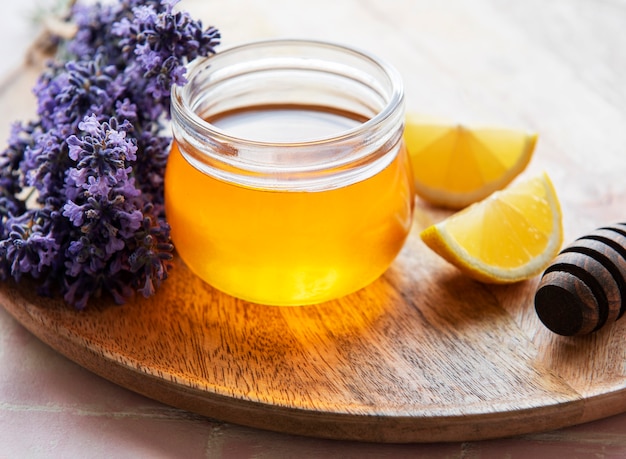 Glas mit Honig und frischen Lavendelblüten auf Holzuntergrund