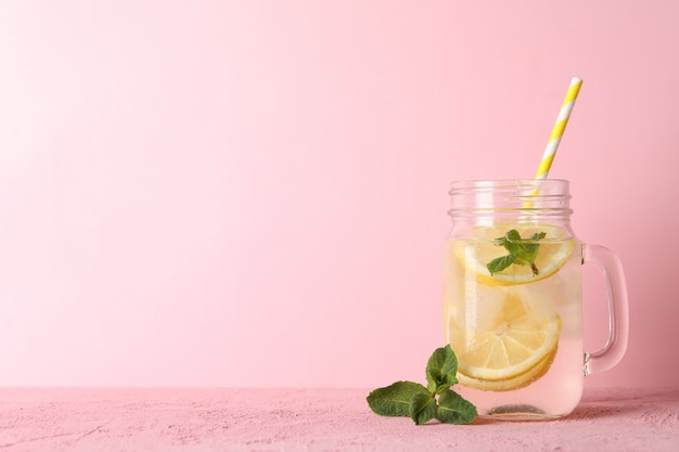 Glas mit Limonade auf rosa Oberfläche. Frisches Getränk