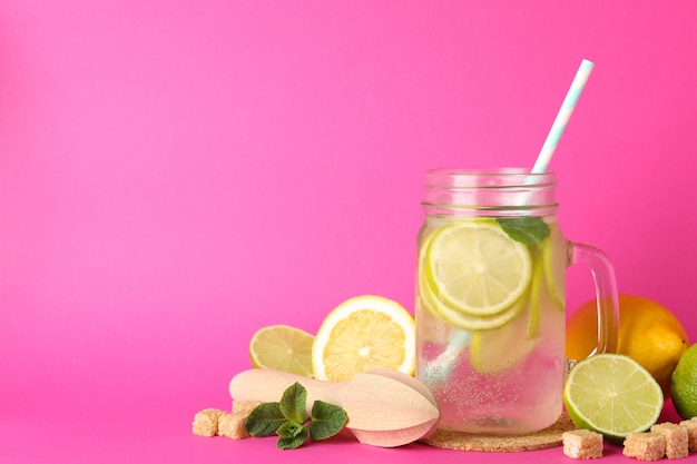 Glas mit limonade und zutaten auf rosa oberfläche