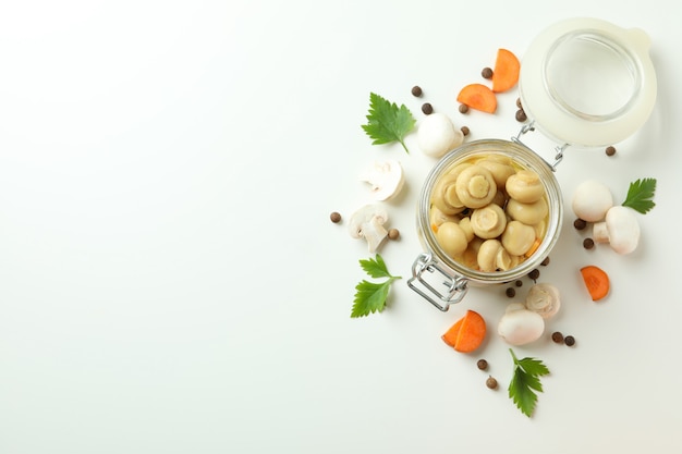 Glas mit marinierten Champignons auf weißem Hintergrund