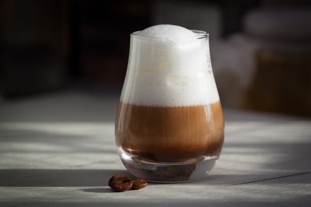 Glas mit milchigem Kaffee Latte oder Cappuccino am Morgen. Sonnenlicht, guten Tag Konzept.