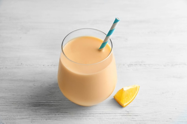 Glas mit orangefarbenem Milchshake auf dem Tisch