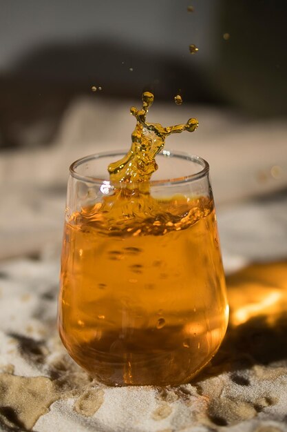 Glas mit Orangengetränk am Sandstrand